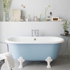 a bathroom with a claw foot bathtub and flowers in vases on the wall