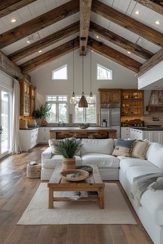 a living room filled with lots of furniture and wooden beams on the ceiling over a kitchen