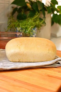 a loaf of bread sitting on top of a wooden table next to a potted plant