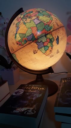 an illuminated globe sits on a table next to two books