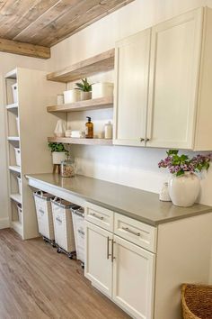 a kitchen with white cabinets and gray counter tops on top of a wooden flooring