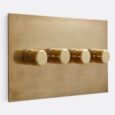 three round knobs are mounted to the side of a gold metal wall light switch