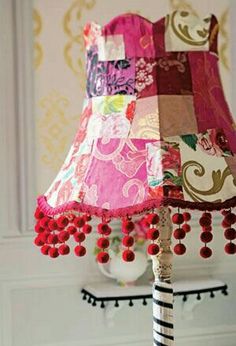 a lamp that is on top of a table with red beads and tassels