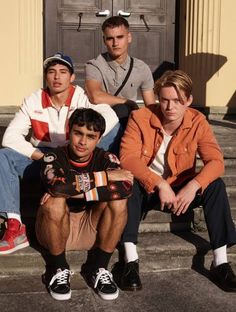 four young men sitting on steps in front of a building