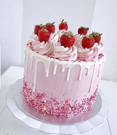 a pink cake with white icing and strawberries on top