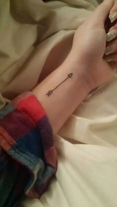 a woman's arm with an arrow tattoo on it