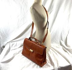 "Measurements are 14\"2 bottom wide, 9\" high, 4\" deep with a 48\" shoulder strap with a 24\" drop. On the interior there are two main compartments, lined in fabric, back zipper pocket and a front top closure. Bag is made of strong leather with light stitching, silver tone hardware, top handle and the shoulder strap is detachable. There are a few scuffs and some marks with no tears and bag is as pictured. Nice leather bag and is perfect for work, school, travel, daily use and looks great. 100% Office Saddle Bag With Adjustable Strap, Workwear Satchel Saddle Bag With Adjustable Strap, Satchel Saddle Bag With Adjustable Strap For Work, Workwear Saddle Bag With Adjustable Strap, Saddle Bag With Adjustable Strap For Business, Office Satchel With Adjustable Strap And Flap, Office Flap Satchel With Adjustable Strap, Formal Satchel Saddle Bag With Adjustable Strap, Workwear Satchel With Adjustable Strap And Flap