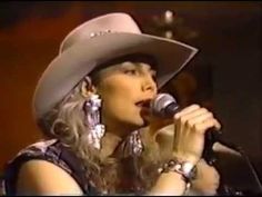 a woman in a cowboy hat singing into a microphone