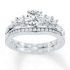 an engagement ring set with two matching bands and a round diamond center stone on the side