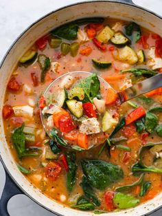 a spoon full of vegetable soup in a pot