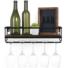 four wine glasses are sitting on a shelf next to bottles and a chalkboard that says bar