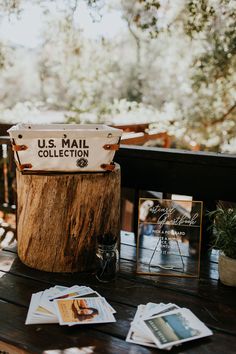 a wooden table topped with photos and a mail box next to a tree stump on top of a deck