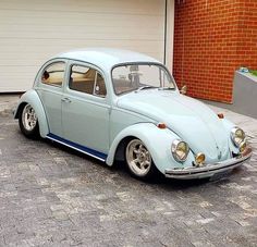 an old blue beetle parked in front of a garage