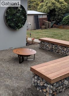 there are two benches and a table in the back yard with gravel on the ground