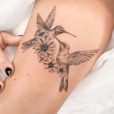 a woman's thigh with a hummingbird and flowers tattoo on it