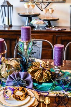 a table topped with purple candles and plates covered in mardi gras cloths