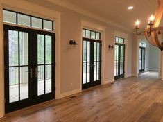 an empty living room with wood floors and black doors