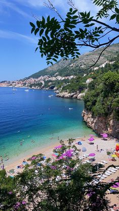 the beach is crowded with people and umbrellas near the water's edge on a sunny day