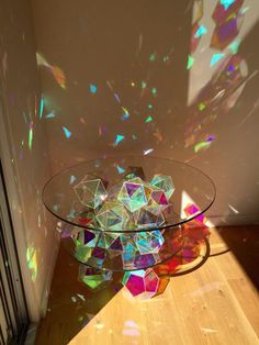 a glass table topped with lots of colorful pieces of art sitting on top of a hard wood floor