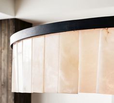 a close up of a light fixture in a room with wood paneling and white curtains