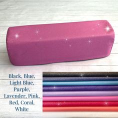 a pink pencil case sitting on top of a white wooden table next to other colored pencils