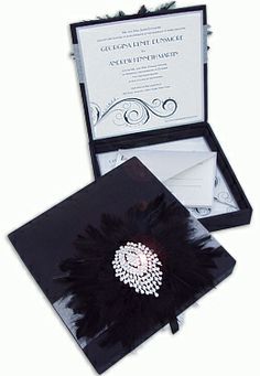 the wedding card is in its box and it has a feathered brooch on top