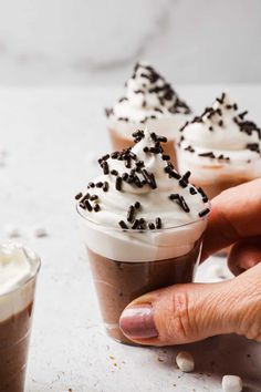 a person holding a cup filled with ice cream and sprinkles on top of it