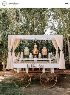 an ice cream cart is set up in front of some trees with drapes on it