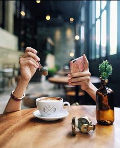 a woman taking a photo with her cell phone while sitting at a table in a coffee shop