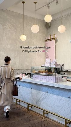 a woman in a trench coat walking past a counter