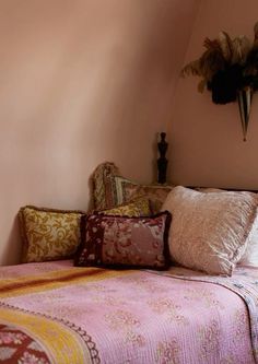 a bed with pink sheets and pillows in a room that looks like it has been made