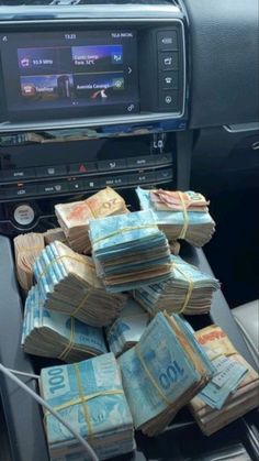 stacks of money sitting on top of a car radio in front of a dash board