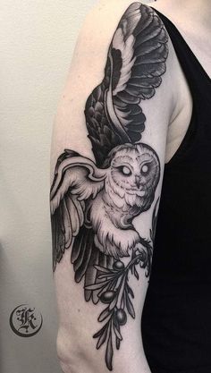 a black and white owl tattoo on the arm