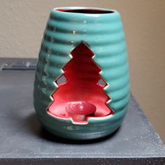 a ceramic cup with a hole in the middle and a red ball inside it on a table