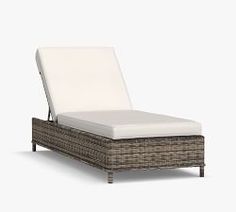 a wicker chaise lounger with white cushions on an isolated gray background,