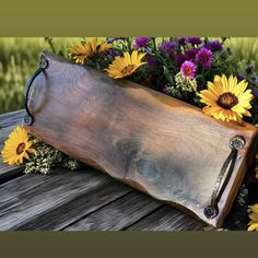 a wooden tray filled with flowers sitting on top of a wooden table next to grass