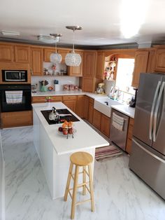 a kitchen with wooden cabinets and white counter tops, an island in the middle has two stools next to it