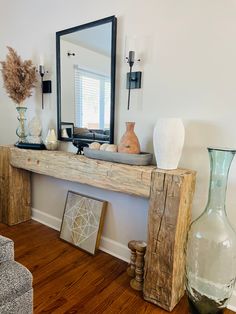 a wooden table topped with vases next to a mirror on top of a wall