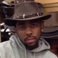 a young man wearing a hat and hoodie in front of a pile of hats