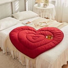 a red heart shaped pillow sitting on top of a bed next to a white nightstand