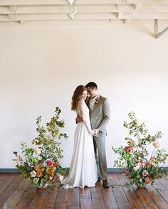 a bride and groom standing next to each other in front of flowers on the floor