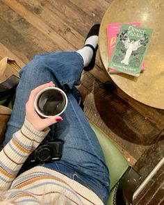 a person laying on the floor holding a coffee cup