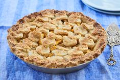 a pie sitting on top of a blue table cloth next to a silver serving spoon