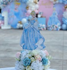 there is a cake with a princess on it and flowers in front of the cake