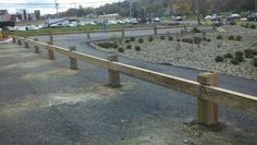 a wooden bench sitting on the side of a road next to a parking lot filled with cars