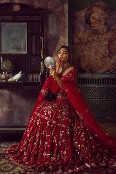 a woman in a red dress is holding a mirror