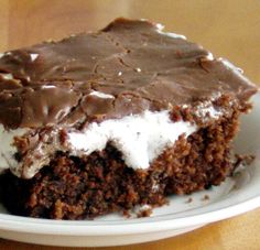 a piece of chocolate cake with white frosting on a plate next to a fork