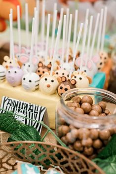 there are many little animals on the table with some candy in front of them,