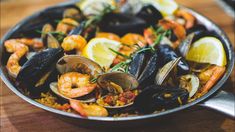 a pan filled with seafood and mussels on top of a wooden table