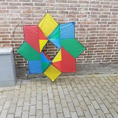 a colorful kite sitting on the ground next to a brick wall